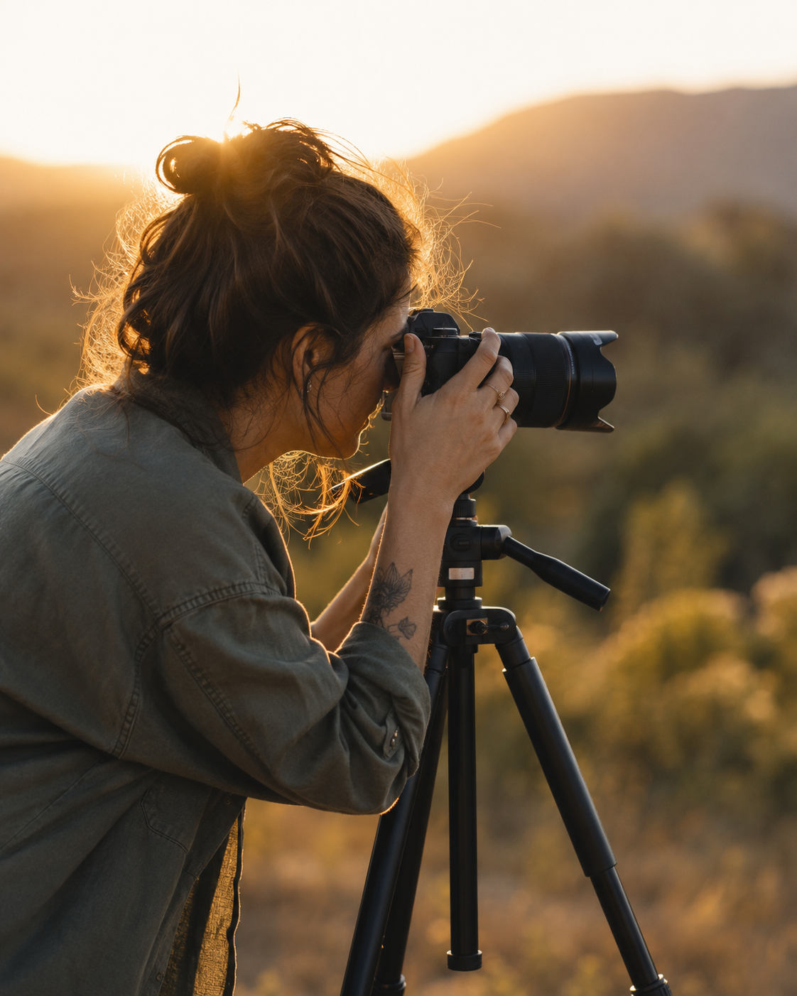 Fotógrafa em ação ao pôr do sol, com câmera profissional, representando o olhar de quem cria